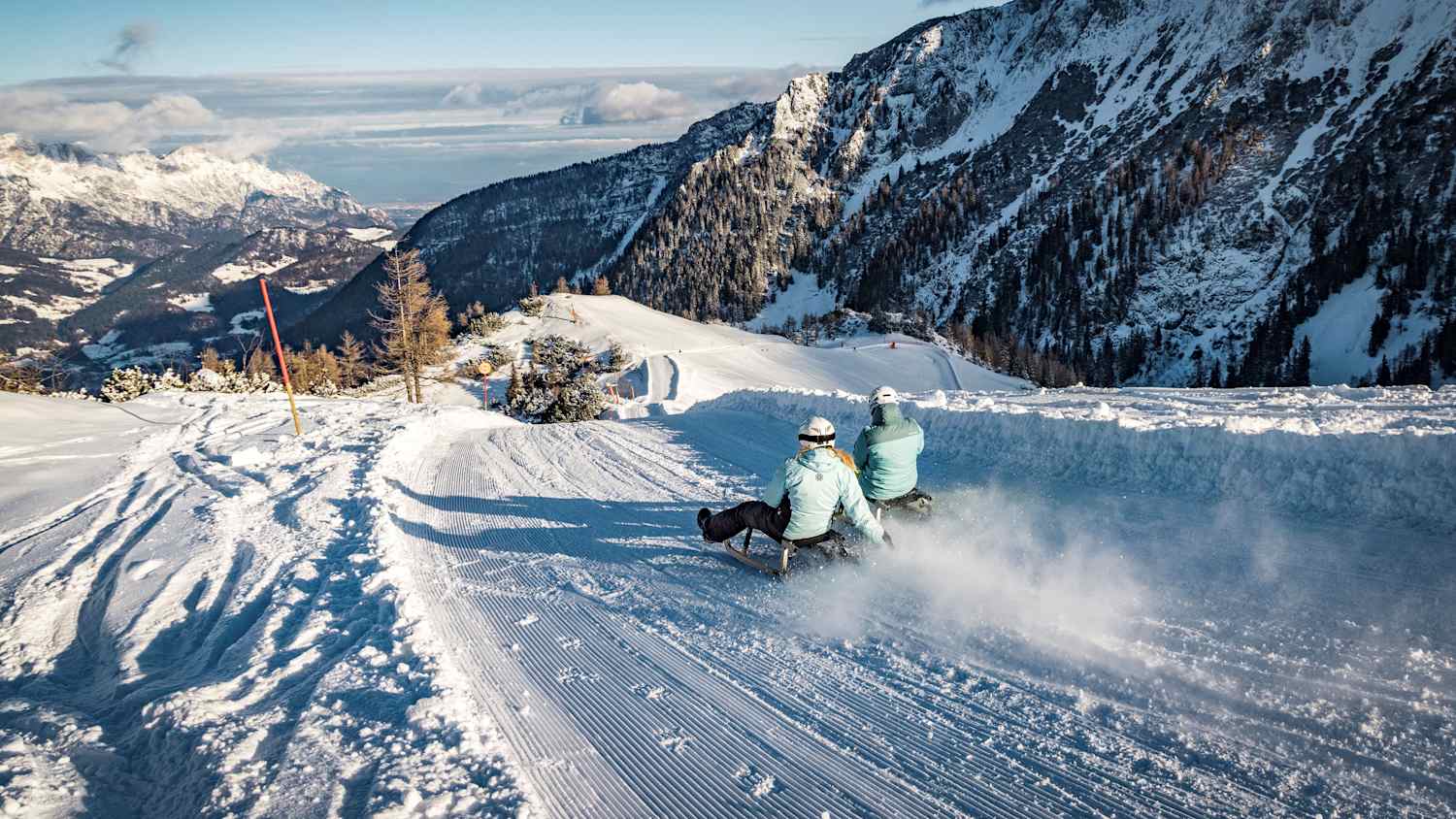 Zwei Rodler fahren die Rodelbahn Jennerhex im Berchtesgadener Land runter