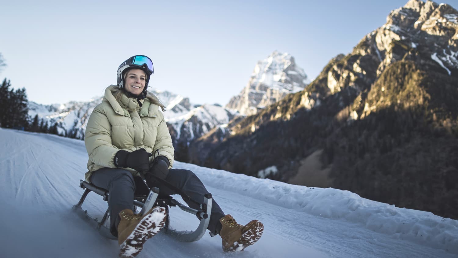 Eine Frau fährt auf dem Schlitten den Berg hinab