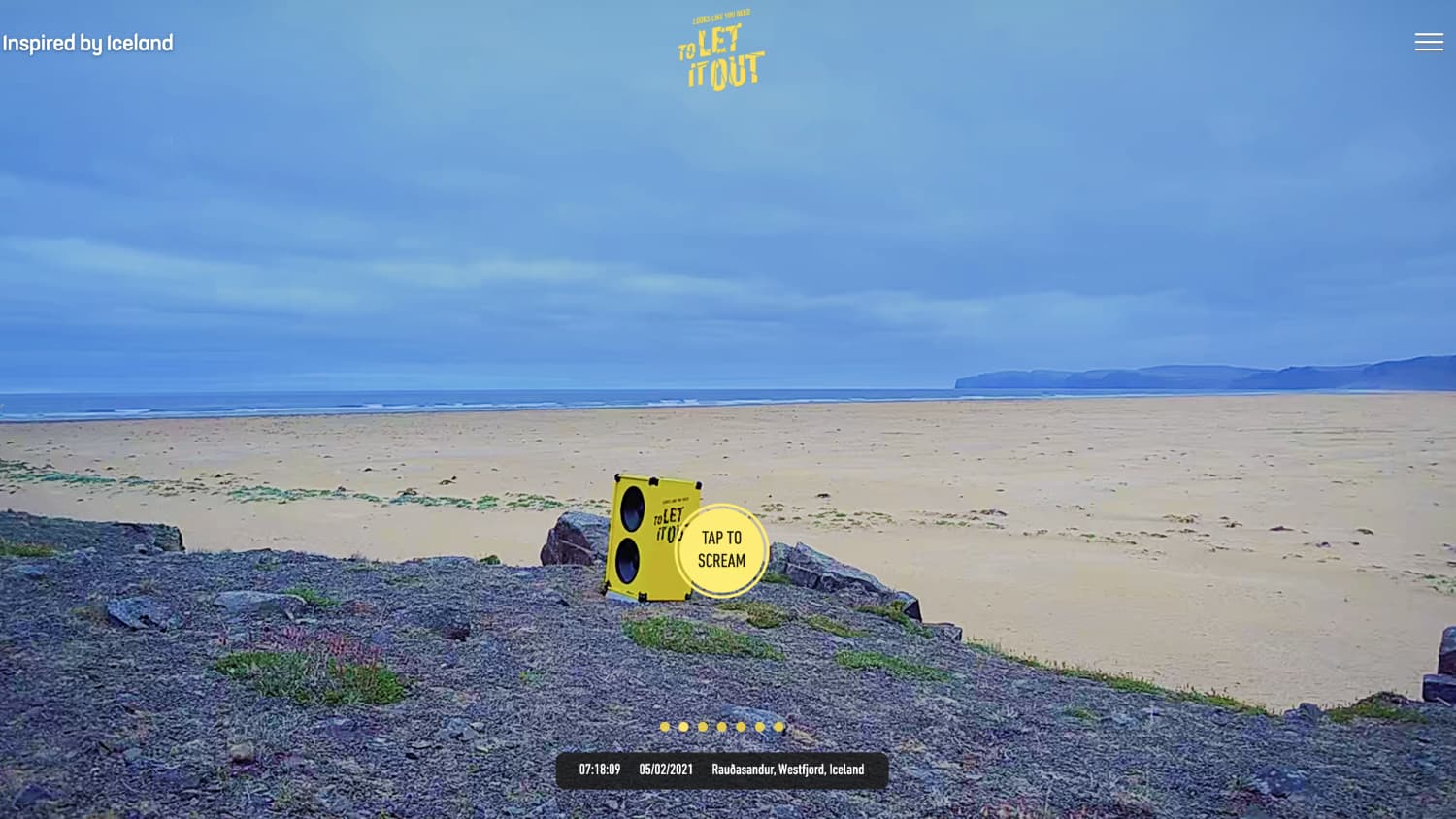 Eine gelbe Lautsprecherbox steht auf Felsen am Strand.
