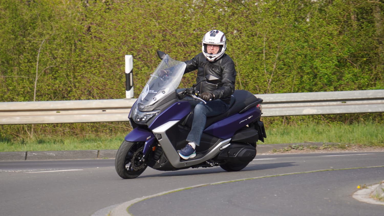 Ein Motorroller Maxsym 400 fährt auf einer Straße