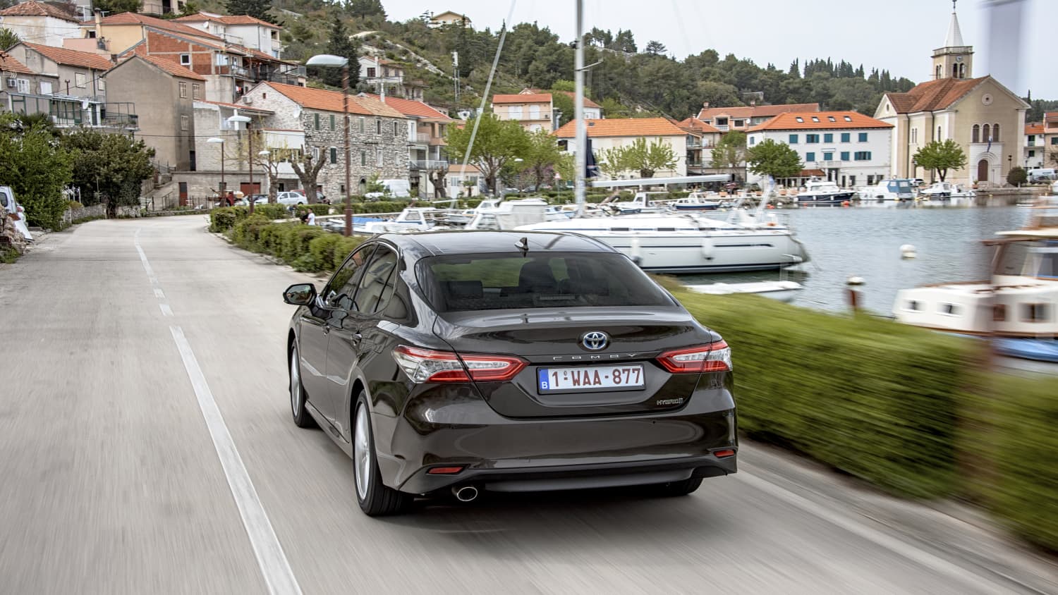 Der Toyota Camry fahrend auf einer Strasse von hinten