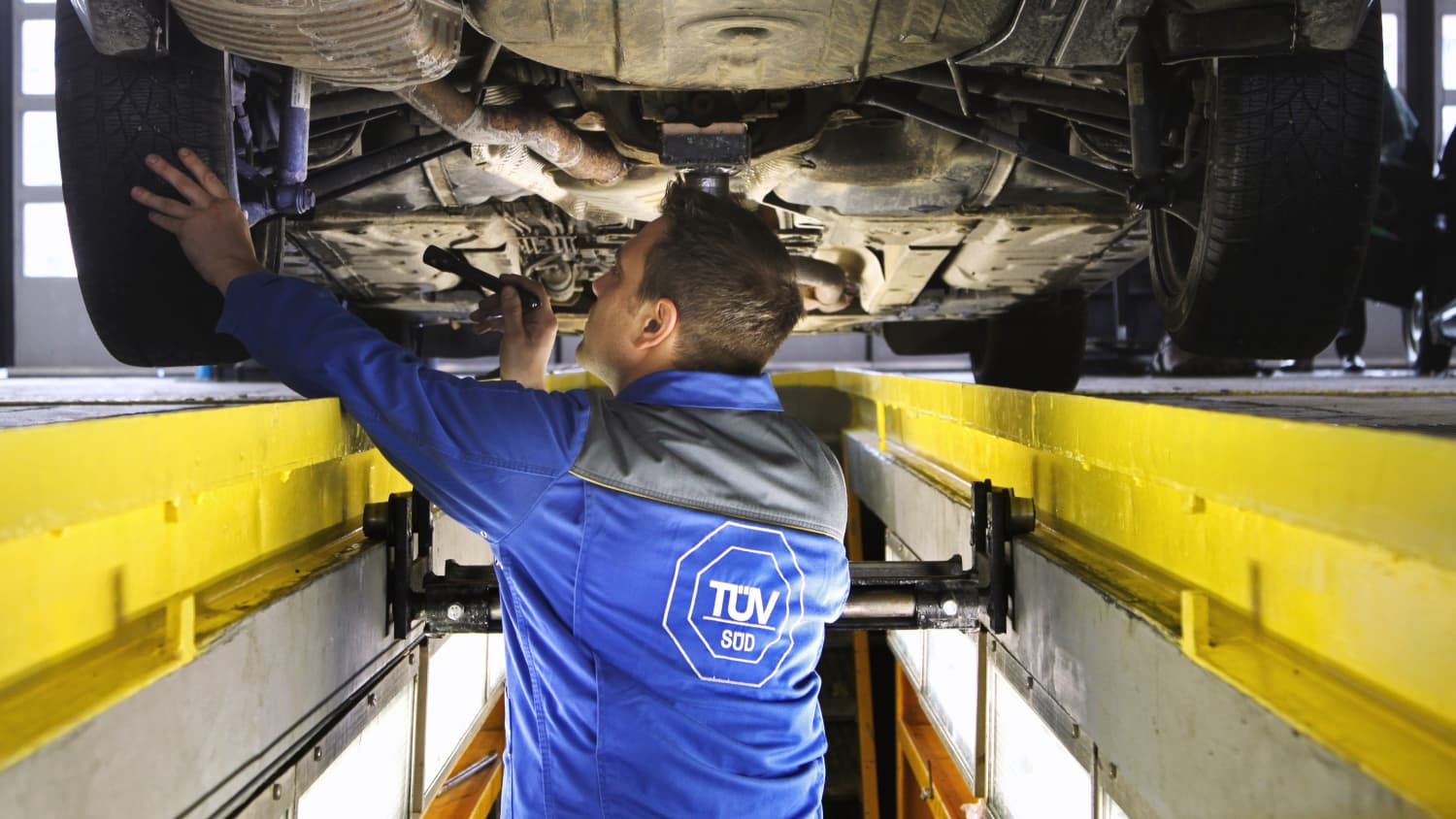 TÜV-Mitarbeiter begutachtet Auto von unten