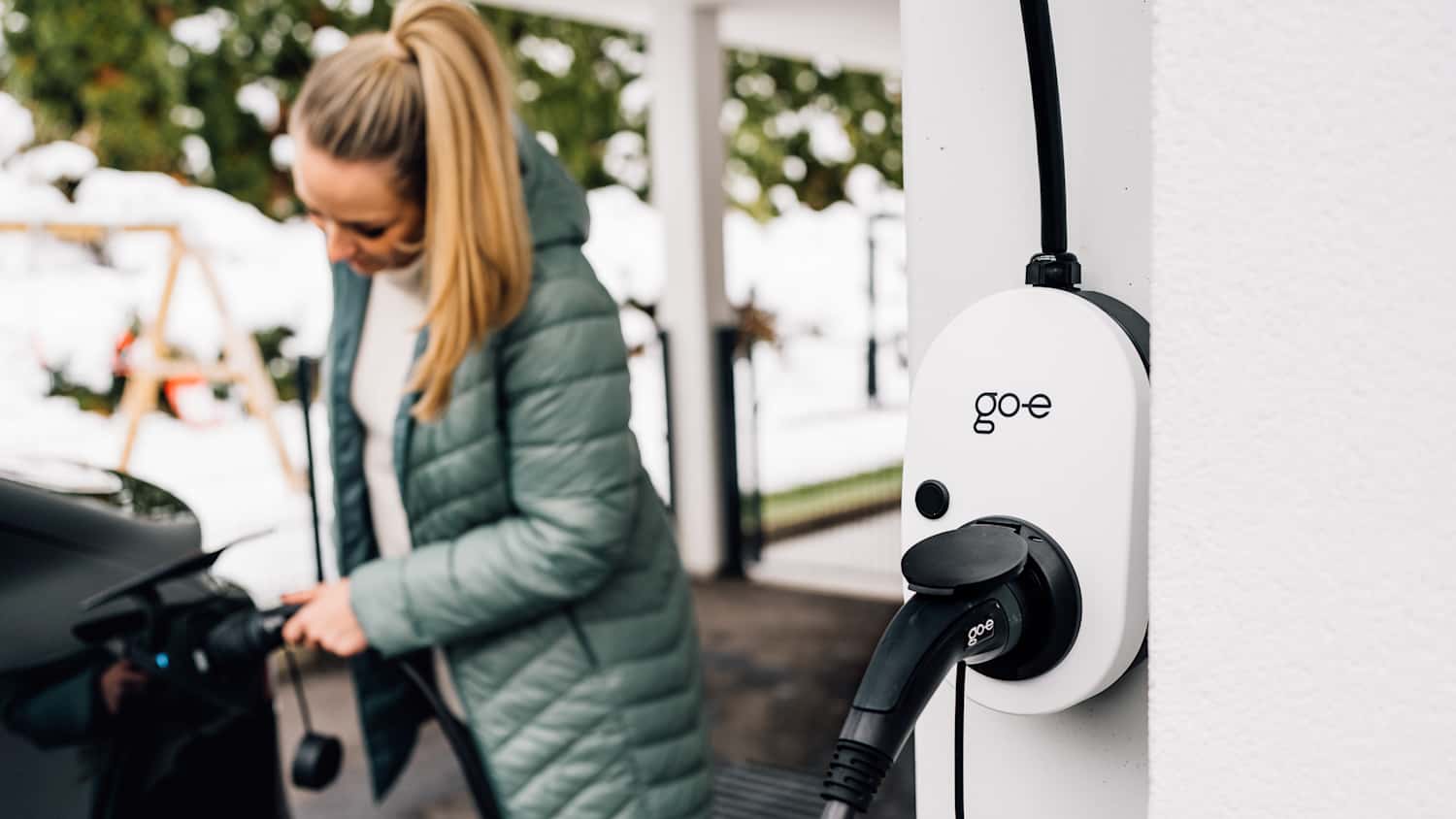 Eine Frau die Ihr Auto lädt und die go-e Wallbox im Vordergrund