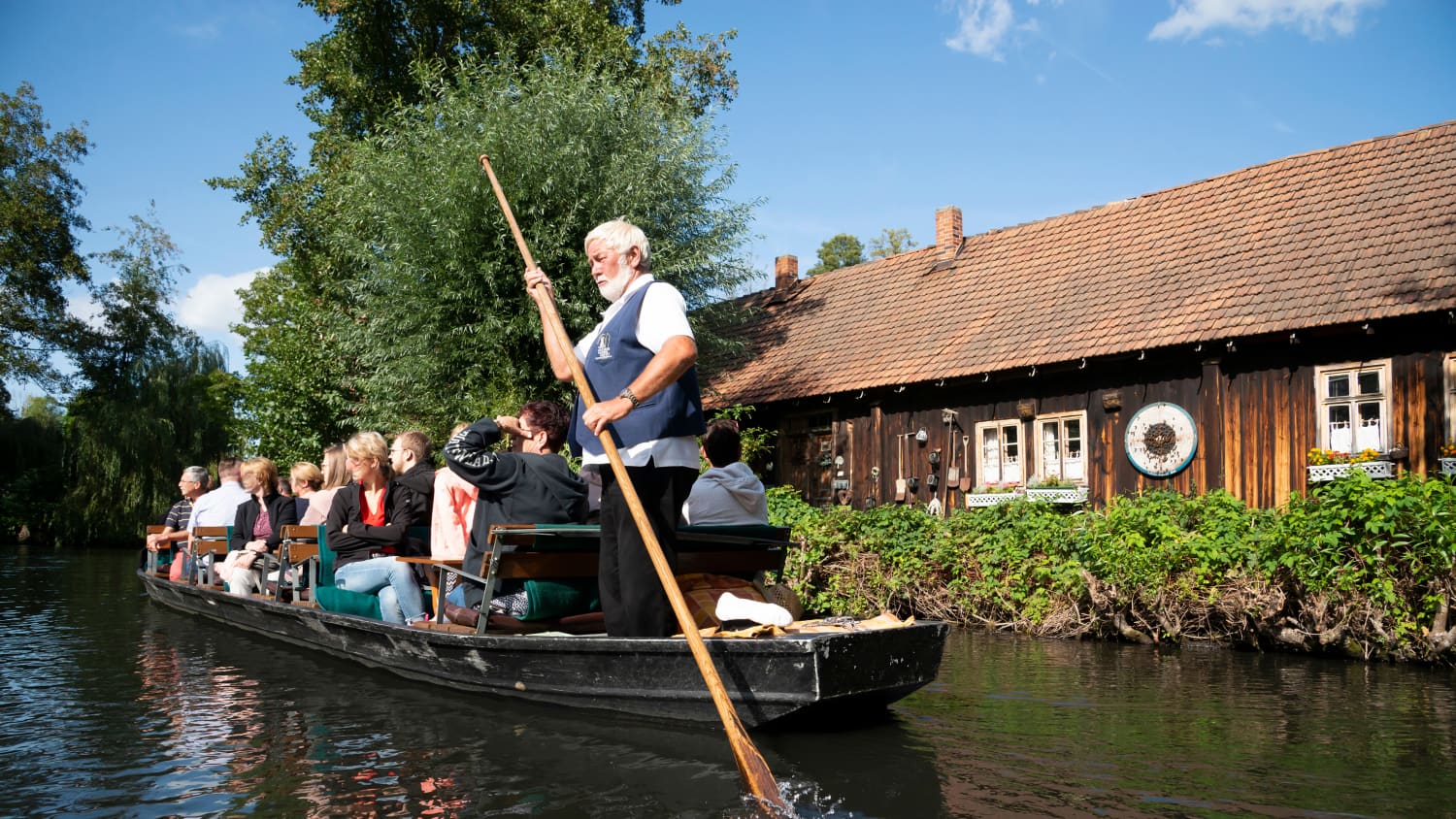 Ein Mann steuert einen Kahn auf einem Fluss mit einer langen Holzstange