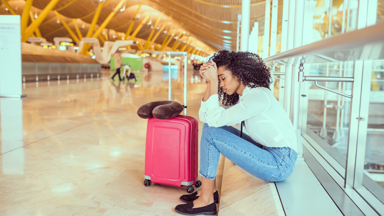 Eine Frau sitzt traurig am Flughafen