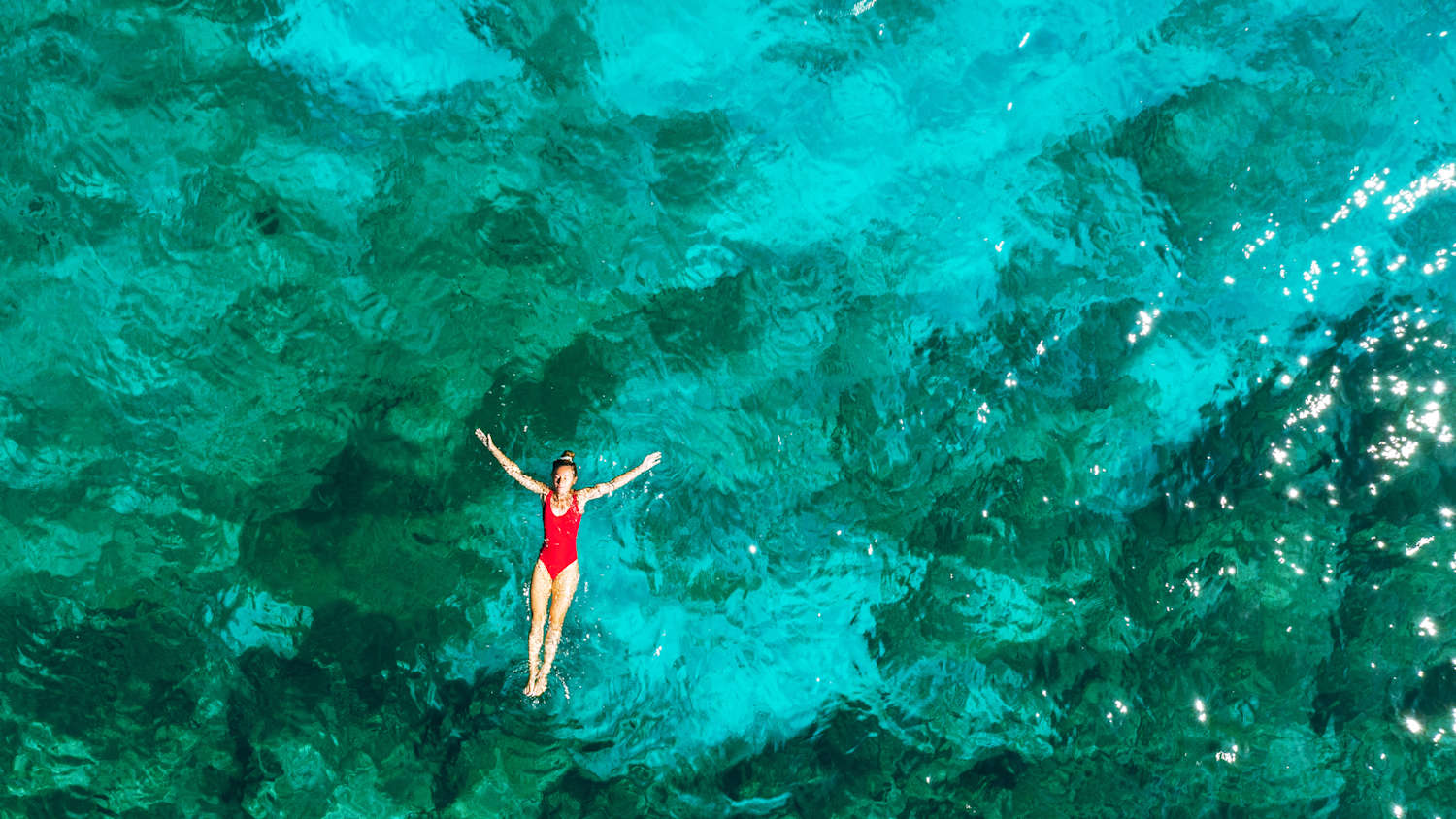 Eine Frau lässt sich im Meer auf dem Rücken treiben