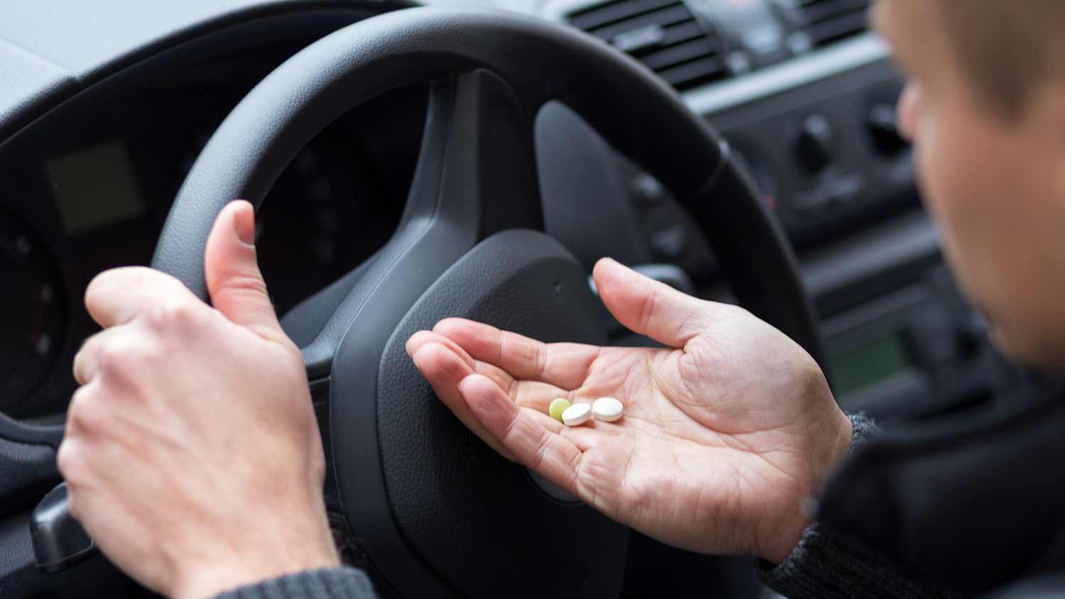 Ein Autofahrer nimmt Tabletten ein