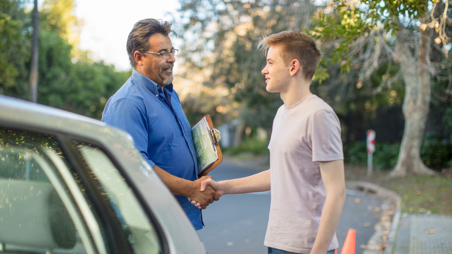 Fahrlehrer gratuliert Schüler zur bestandenen Führerscheinprüfung