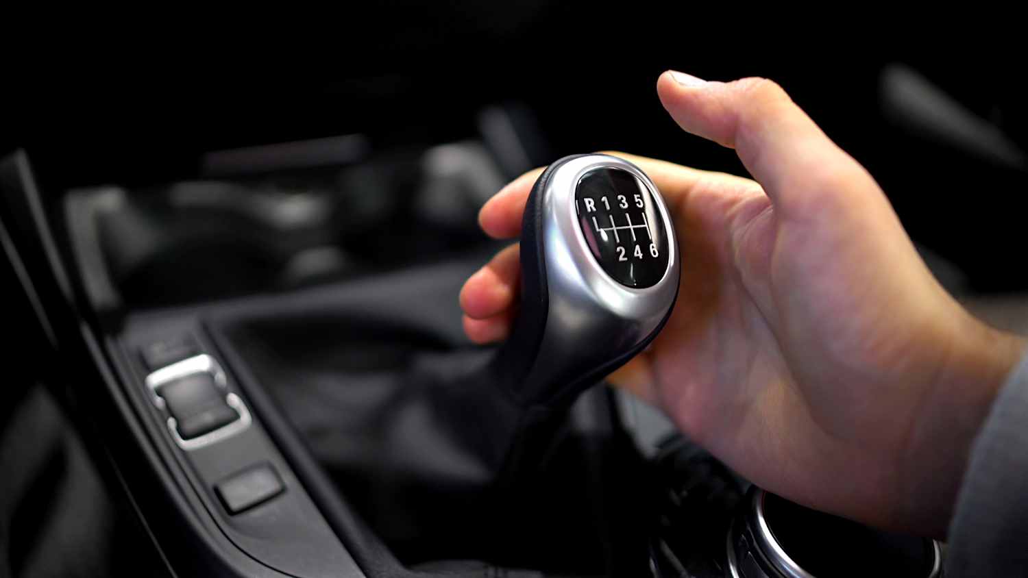 Eine Hand liegt an einer Autoschaltung mit Schaltgetriebe