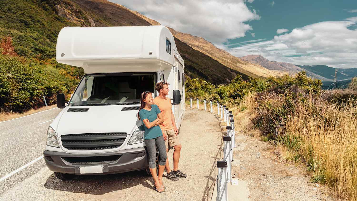 Ein junges Paar lehnt an ihrem Wohnmobil und genießt die Aussicht