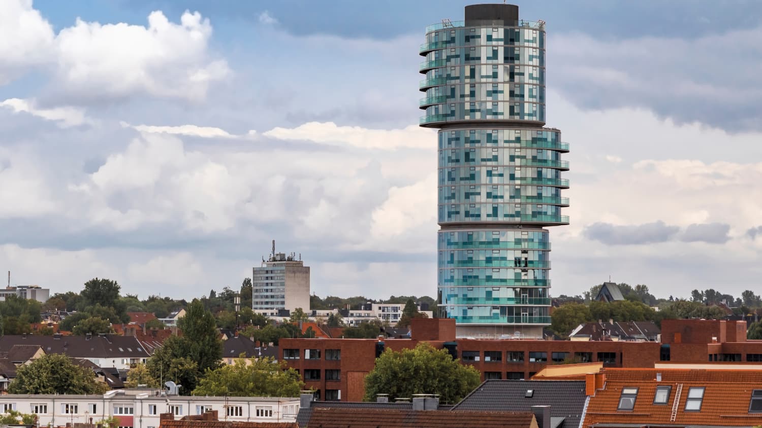 Ein rundes Hochhaus, unterteilt in drei Stücke, die nicht verschoben aufeinander sitzen.