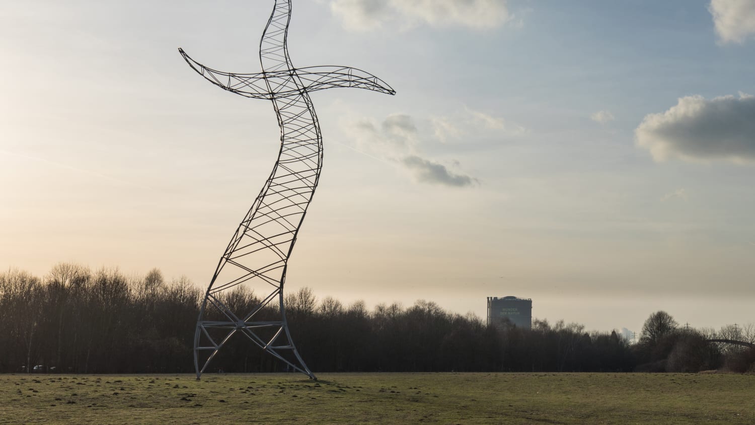 Ein Strommast, der so aussieht, als ob er tanzen würde steht auf einem Feld.