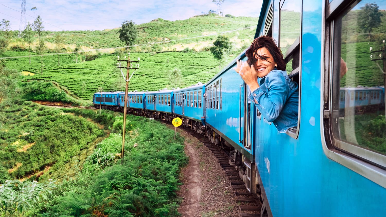 Eine Frau schaut aus dem Fenster eines fahrenden Zuges in Sri Lanka auf Teeplantagen.