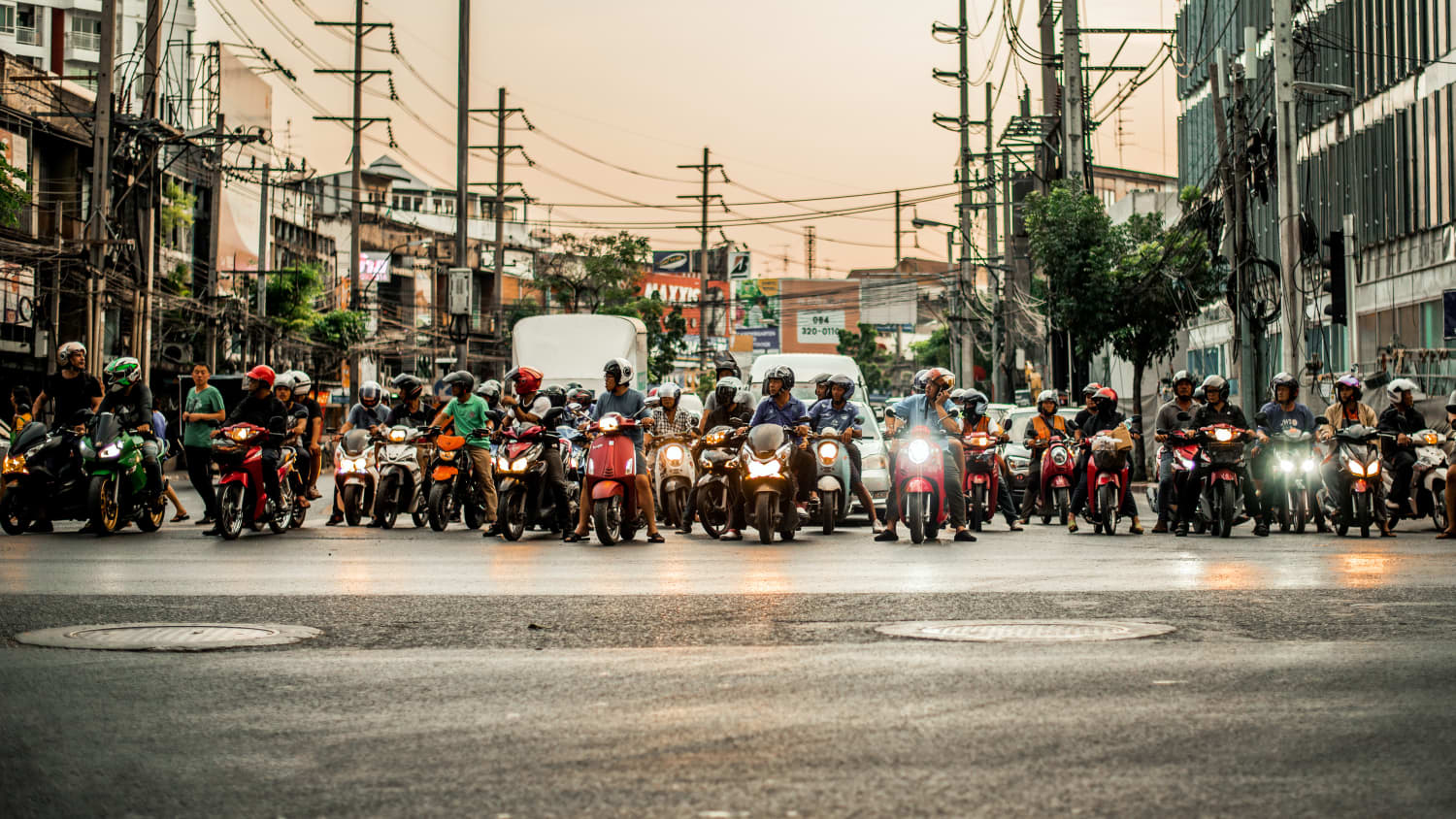 Viele Mopeds stehen auf einer stark befahrenen Strasse in Thailand