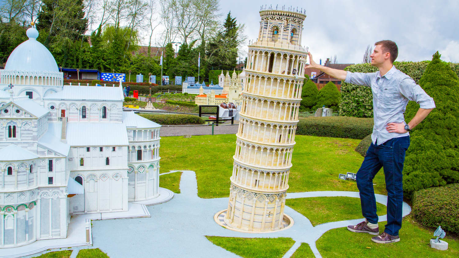 Ein Mann steht neben einer Miniaturausgabe des Schiefen Turms von Pisa im Mini Europe in Brüssel
