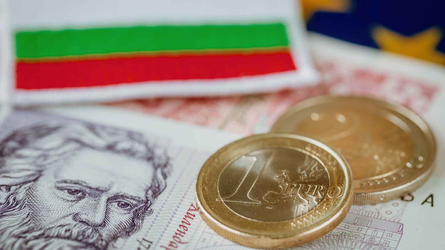 Euromünzen und Bulgarische Scheine liegen auf einer Europaflagge