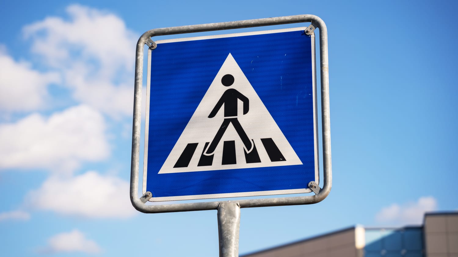 Zebrastreifen Verkehrsschild vor blauem Himmel mit Wolken