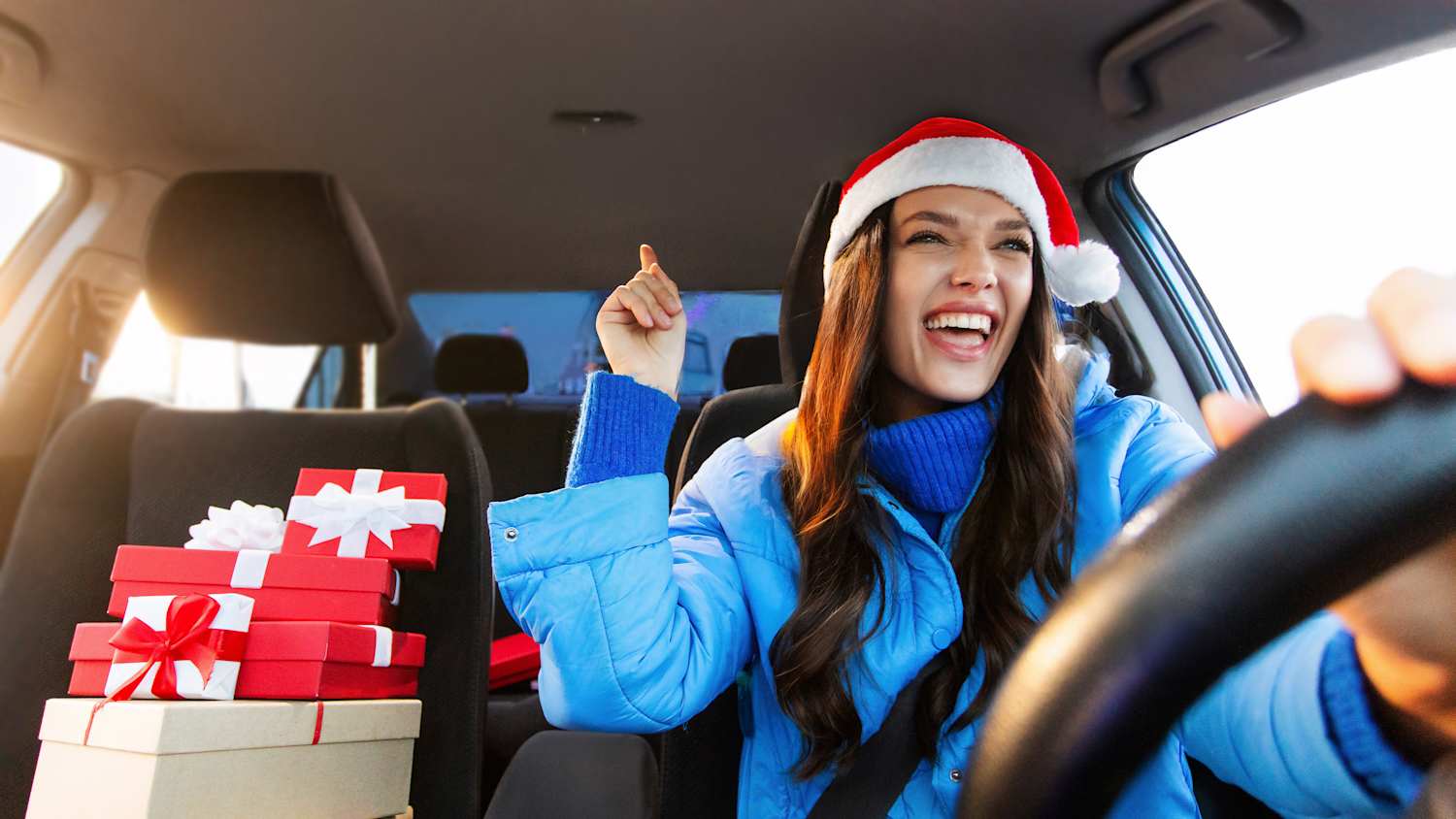 Eine Frau mit Weihnachtsmannmütze singt beim Autofahren