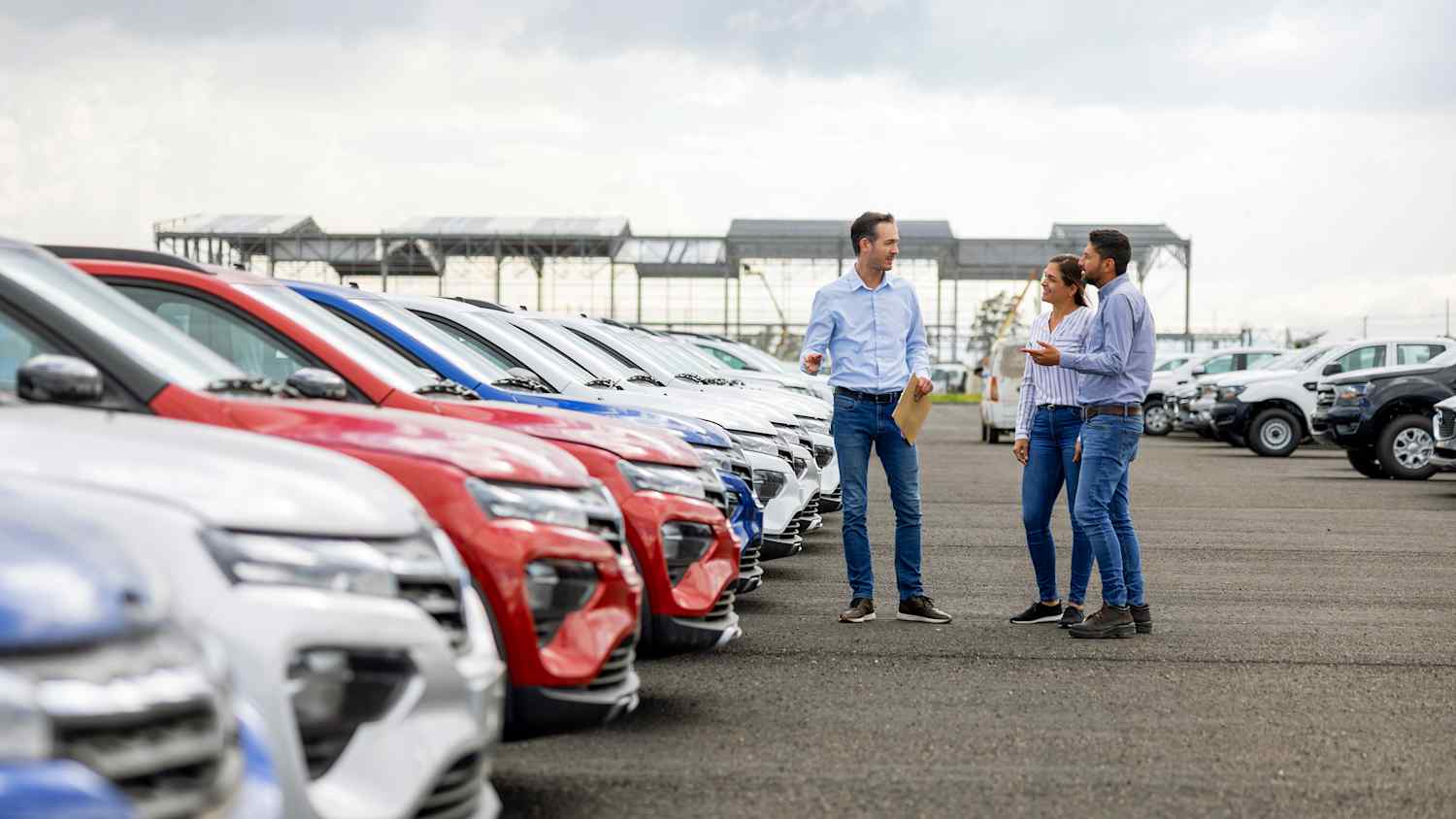 Ein Paar lässt sich von einem Verkäufer bzgl. des Autokaufs beraten