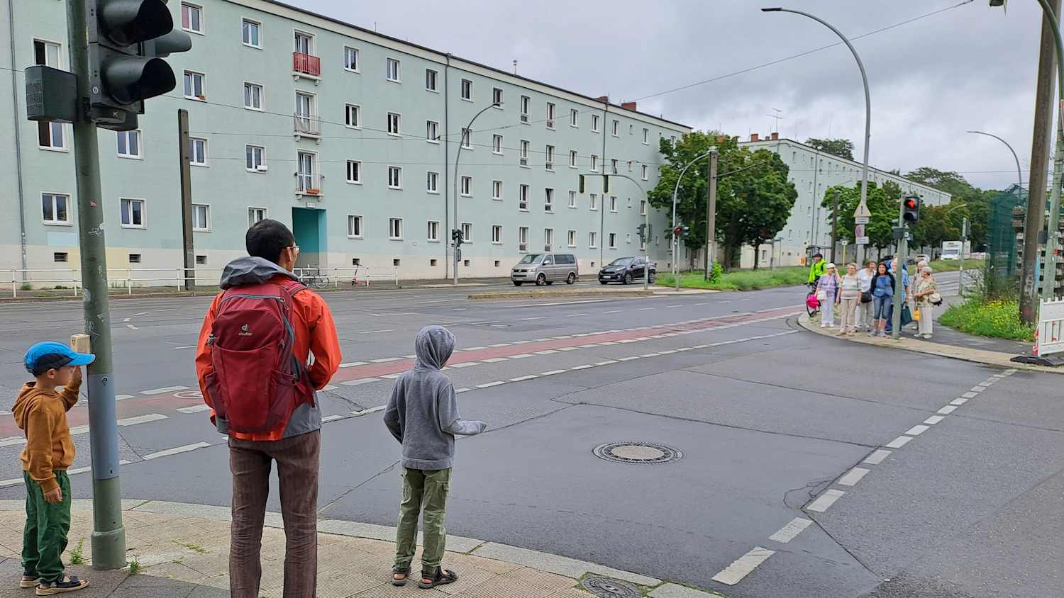 Ein Vater wartet mit seinen beiden Kindern an einer roten Fußgängerampel