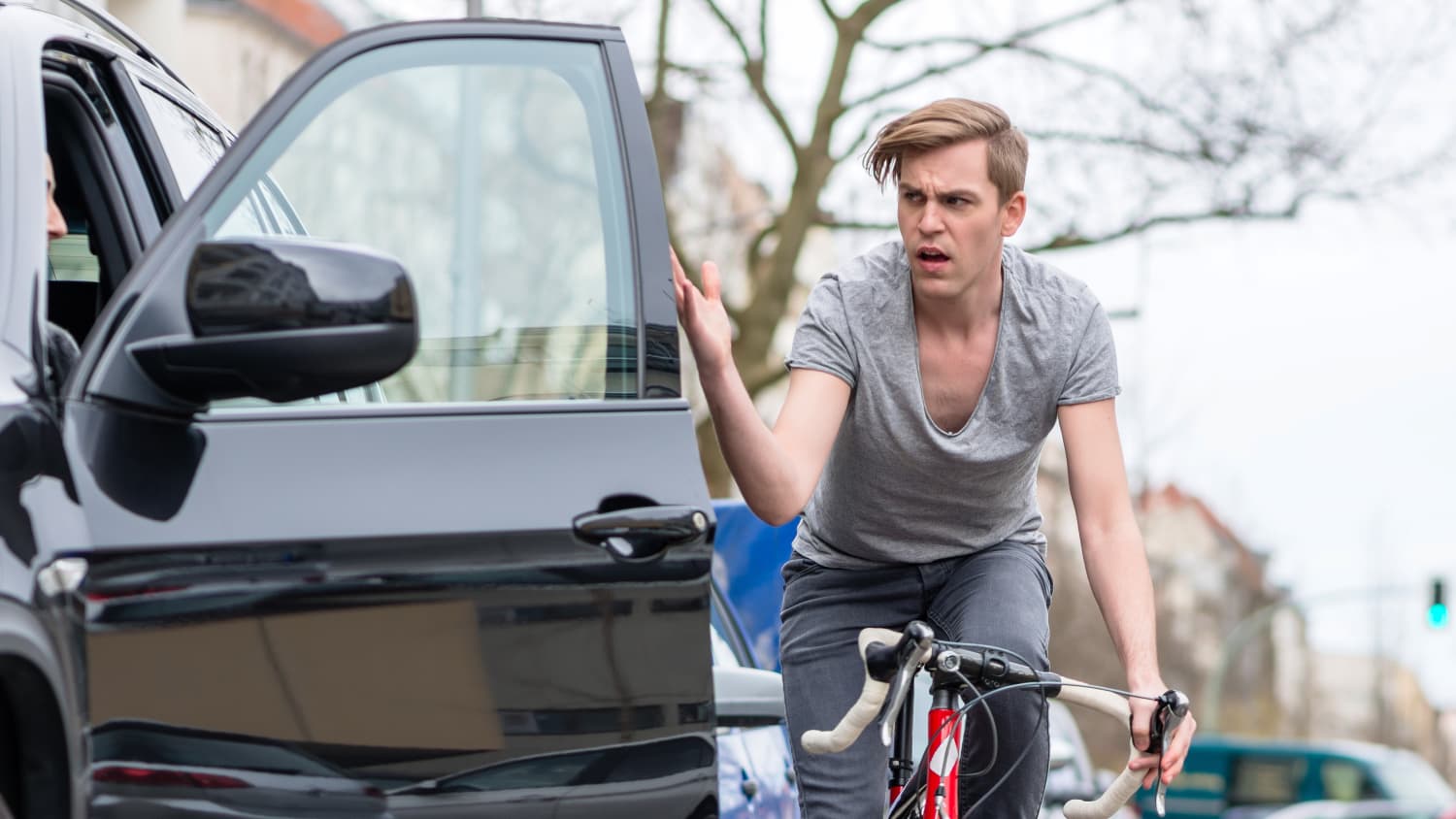 Ein Fahrradfahrer ist wütend weil er beinahe gegen eine sich öffnende Autotür gefahren wäre