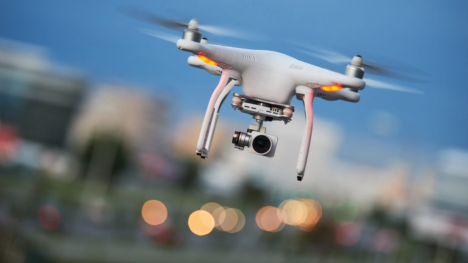 Drohnenquadcopter mit Digitalkamera, der im abendblauen Himmel über der Stadt fliegt oder schwebt