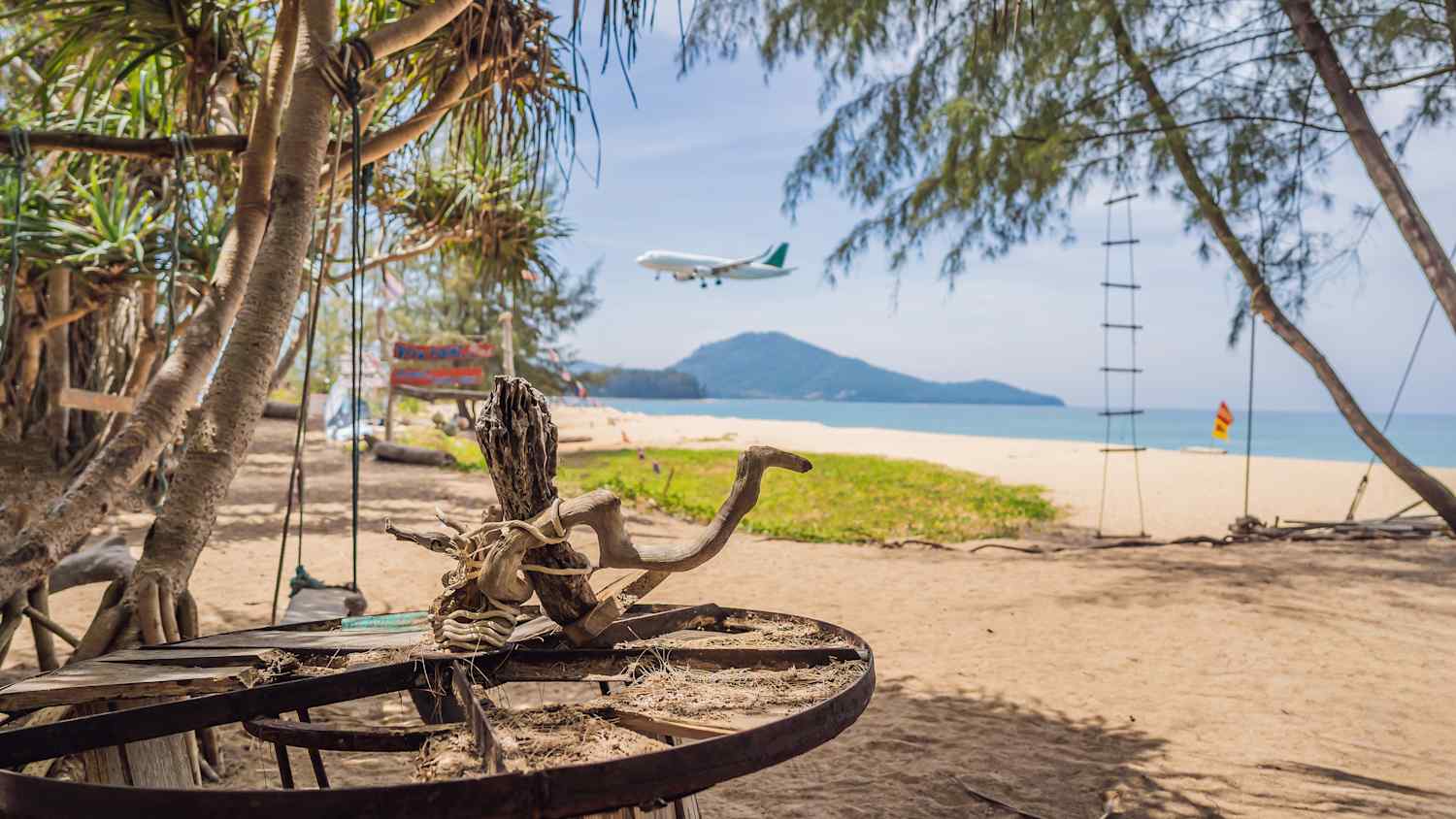 Ein Strand in Thailand mit einem Flugzeug im Landeanflug zu sehen  im Hintergrund
