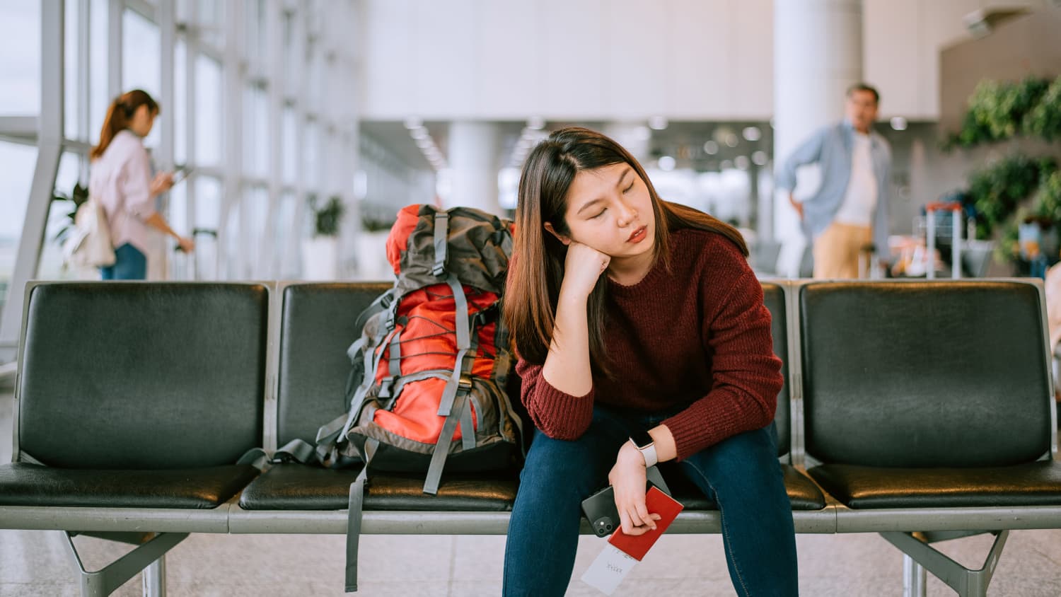 Eine junge asiatische  Frau wartet am Flughafen auf ihren Flug
