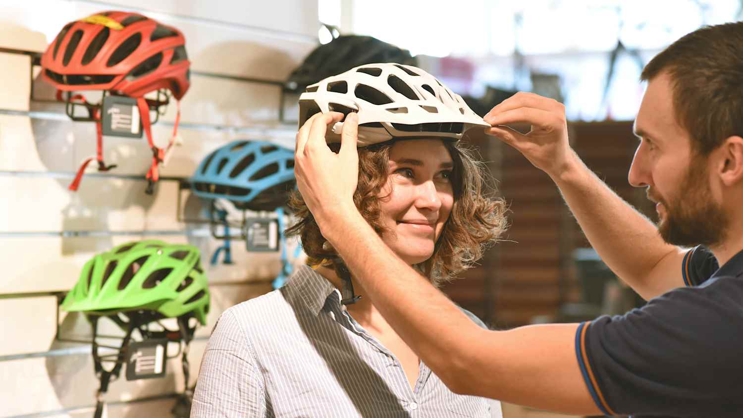 Ein Verkäufer berät eine Frau beim Fahrradhelm kauf