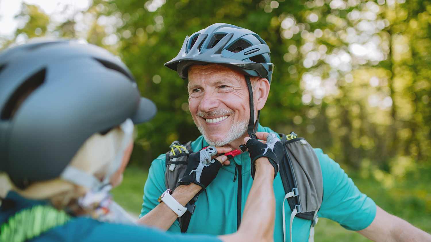 Eine Frau schliesst den Verschluss am Fahrradhelm ihres Mannes
