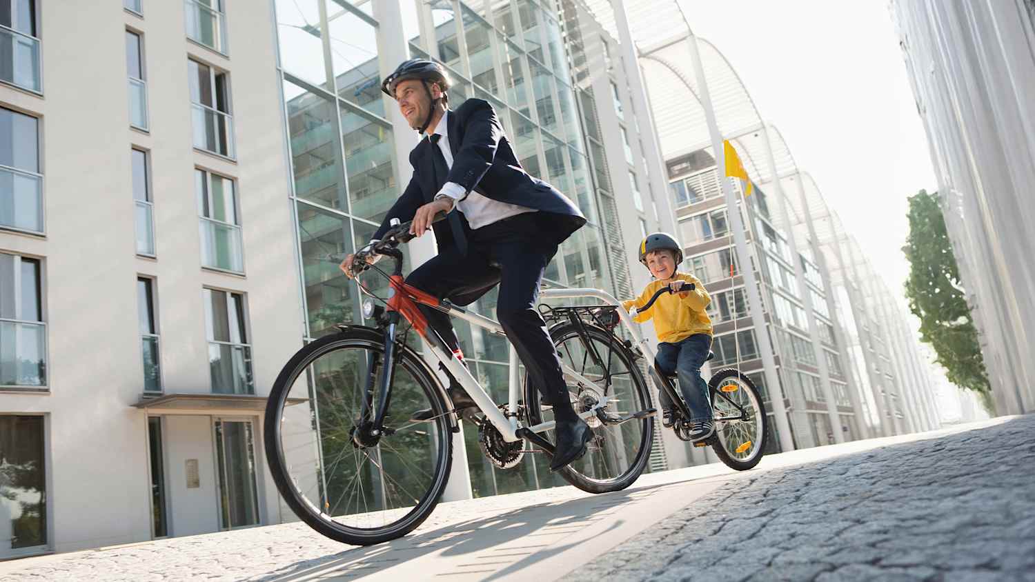 Vater und Sohn fahren gemeinsam Fahrrad auf der Stadtstraße mit einem Nachläufersystem