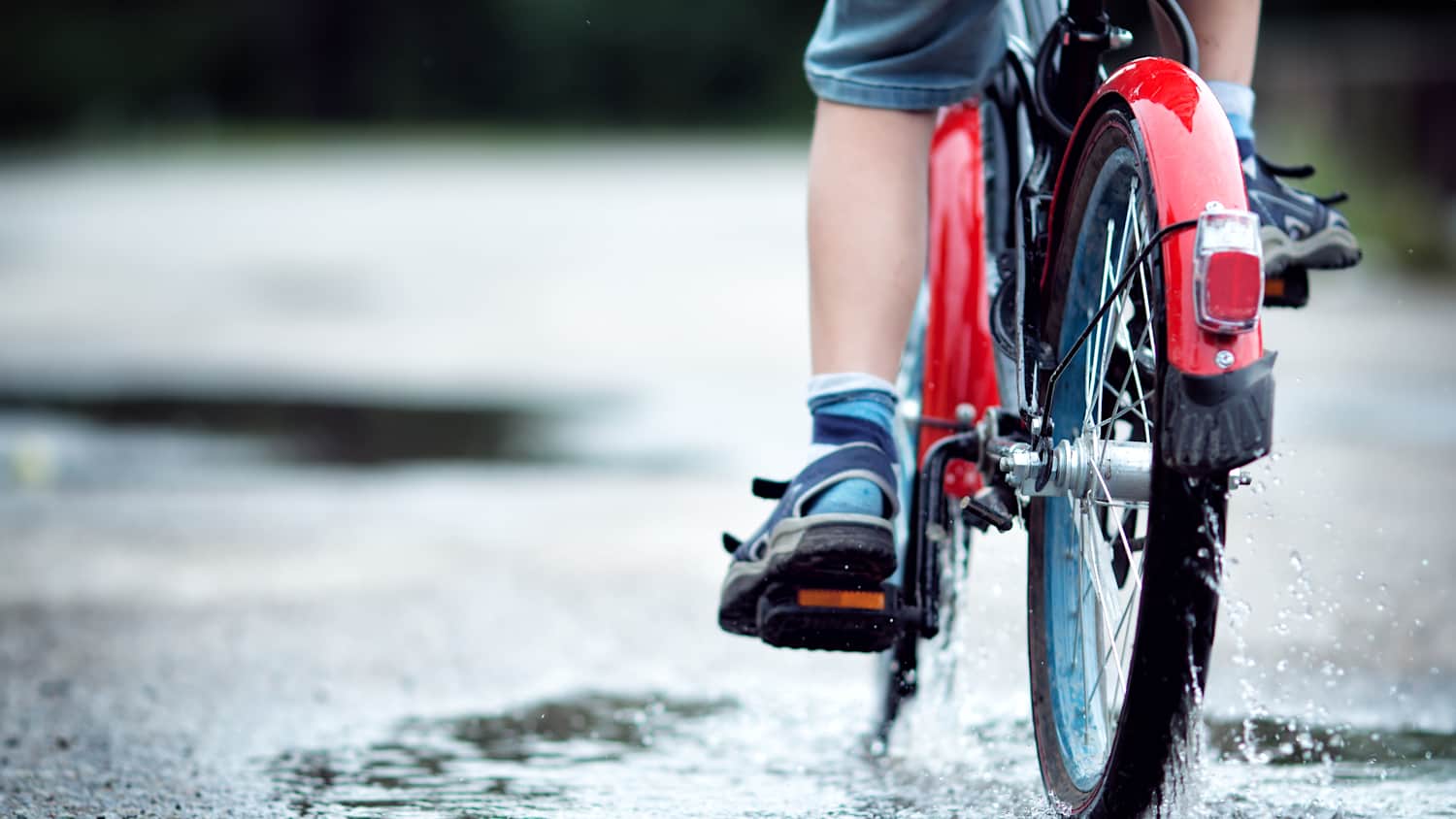 Ein Kind fährt mit dem fahrrad durch eine Pfütze