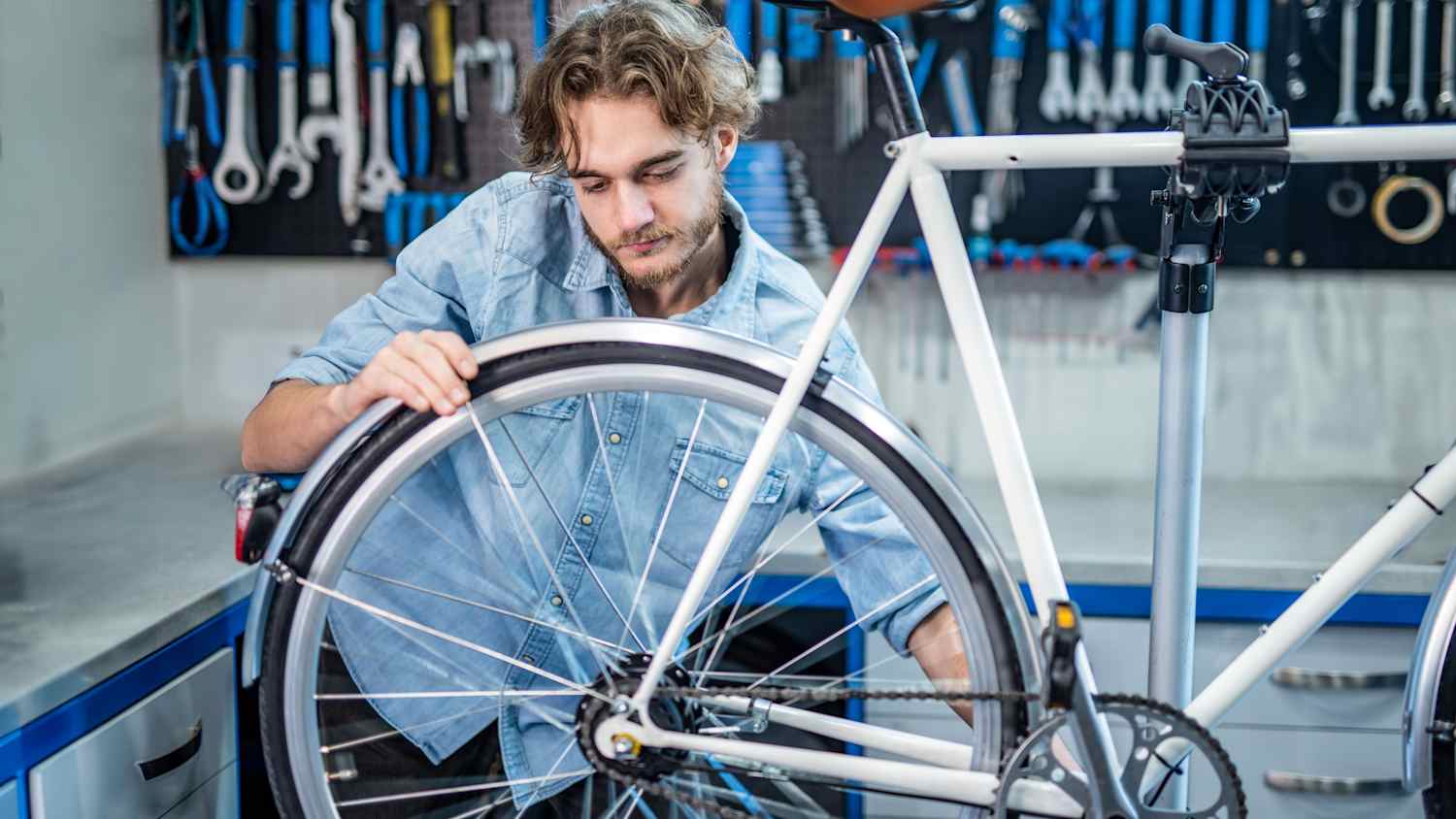 Ein Mann montiert bei sich in der Garage ein Schutzblech an das Hinterrad seines Fahrrades