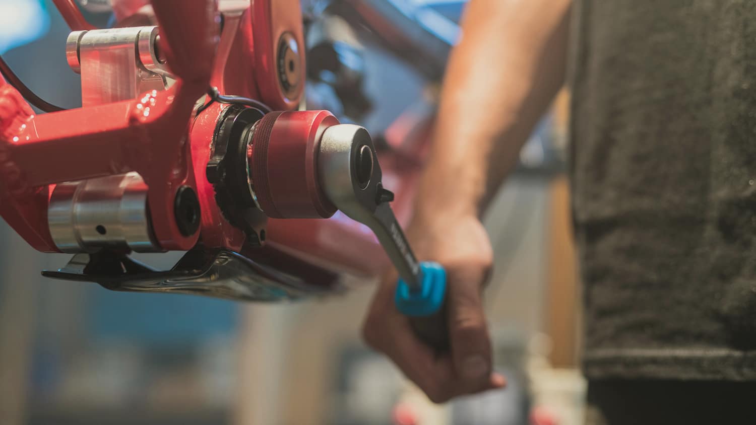 Ein Mann der mit einem Schraubenschlüssel ein Tretlager an einem Downhill-Fahrrad festzieht.