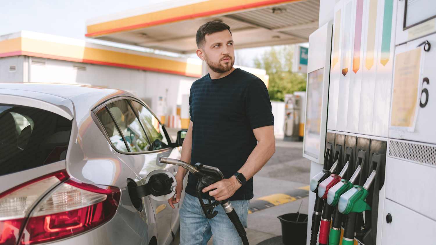 Ein Mann überlegt an einer Tankstelle was er tanken muss