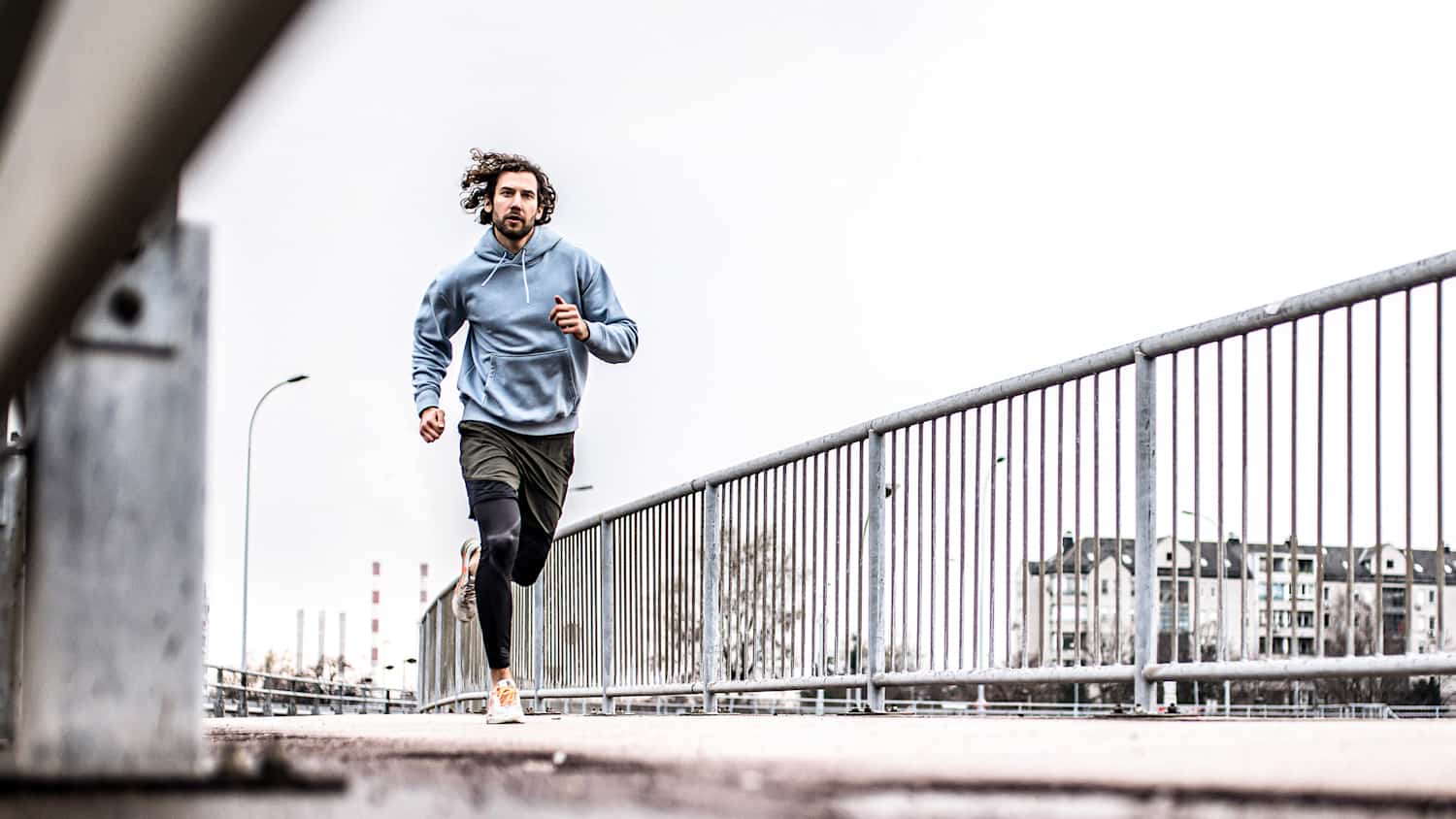 Ein Mann joggt bei tristem Winterwetter auf einem Gehweg