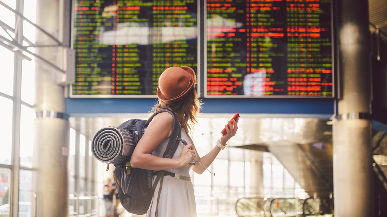 Eine junge Frau schaut auf die Anzeigetafel an einem Flughafen