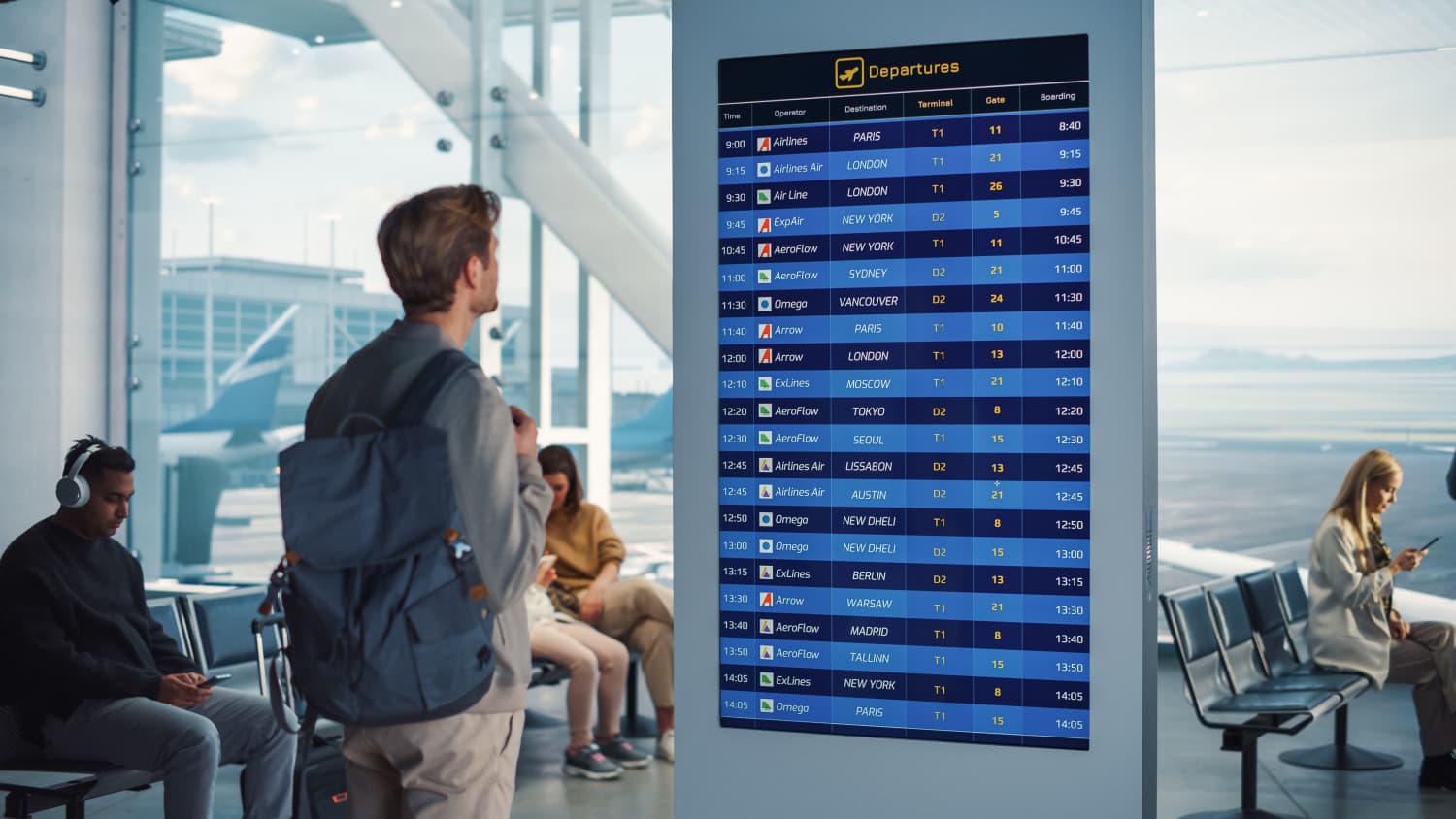 Ein Mann mit Rucksack steht vor einer Abflugtafel am Flughafen