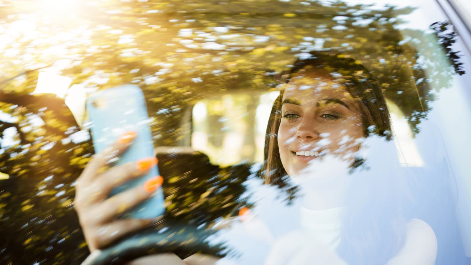 Eine Junge Frau fährt Auto mit dem handy in der Hand