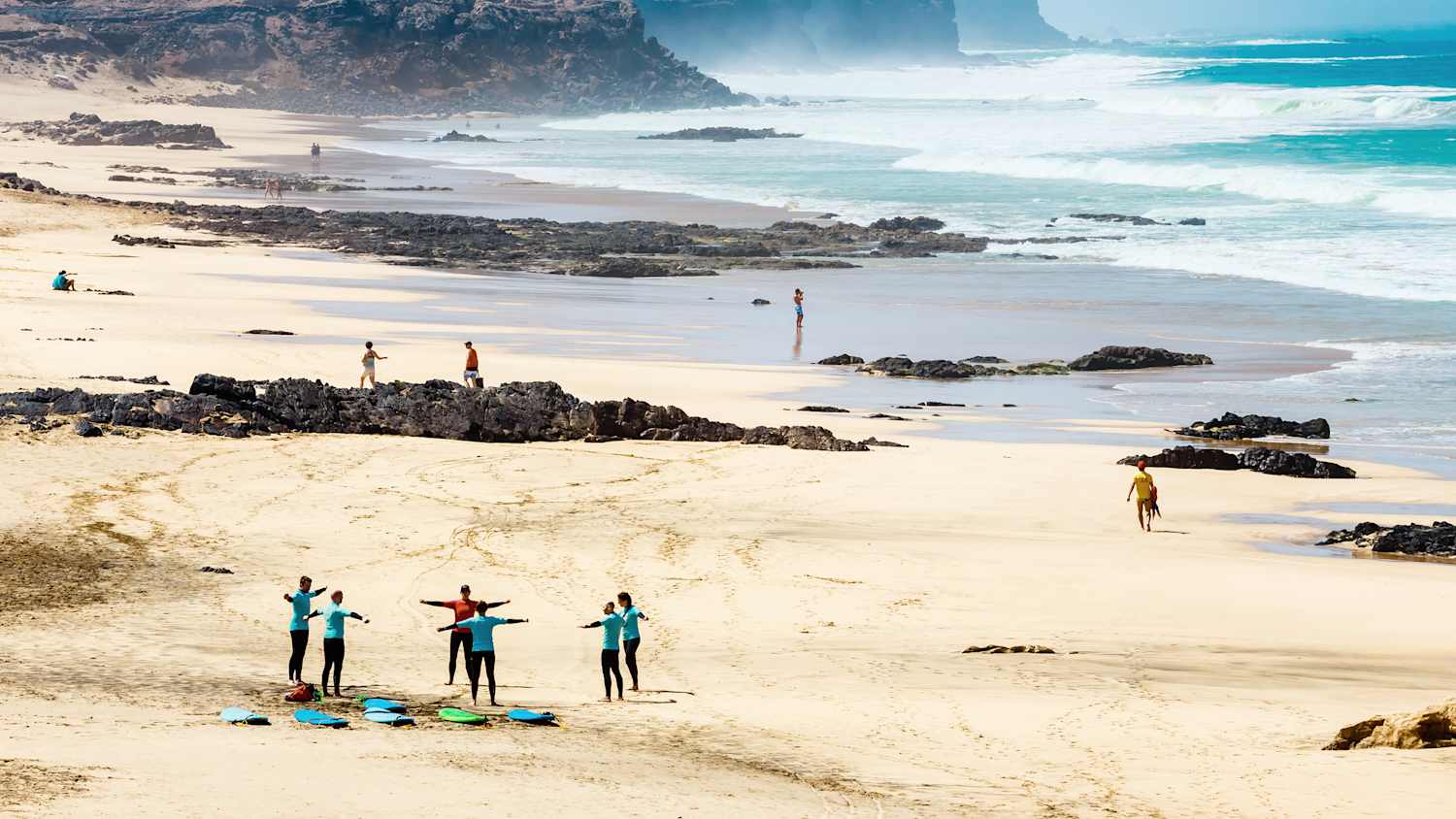Aufnahme auf Fuerteventura bei welchem sich Surfer am Strand von El Castillo aufwärmen