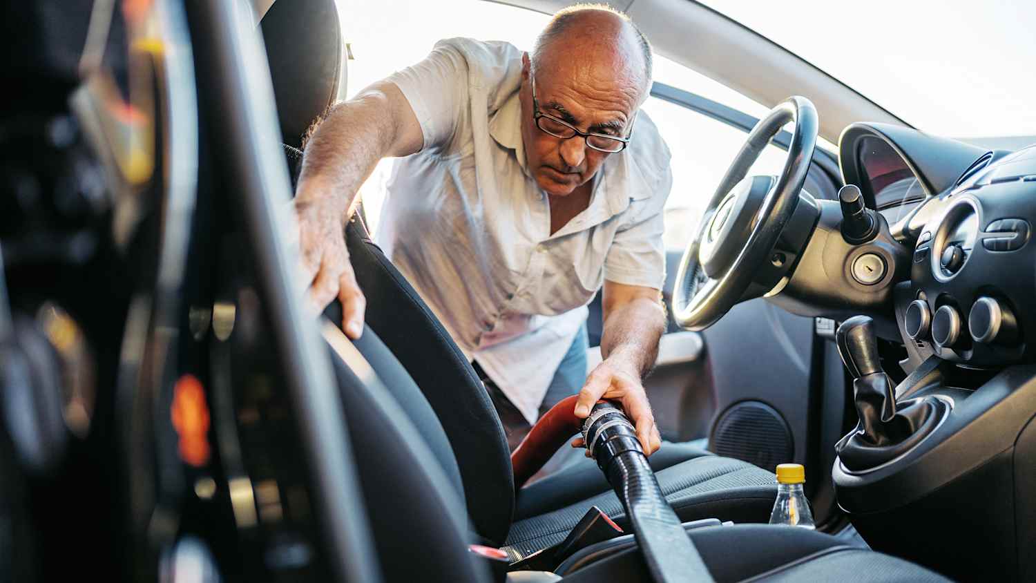 Ein älterer Mann saugt die Sitze seines Autos ab