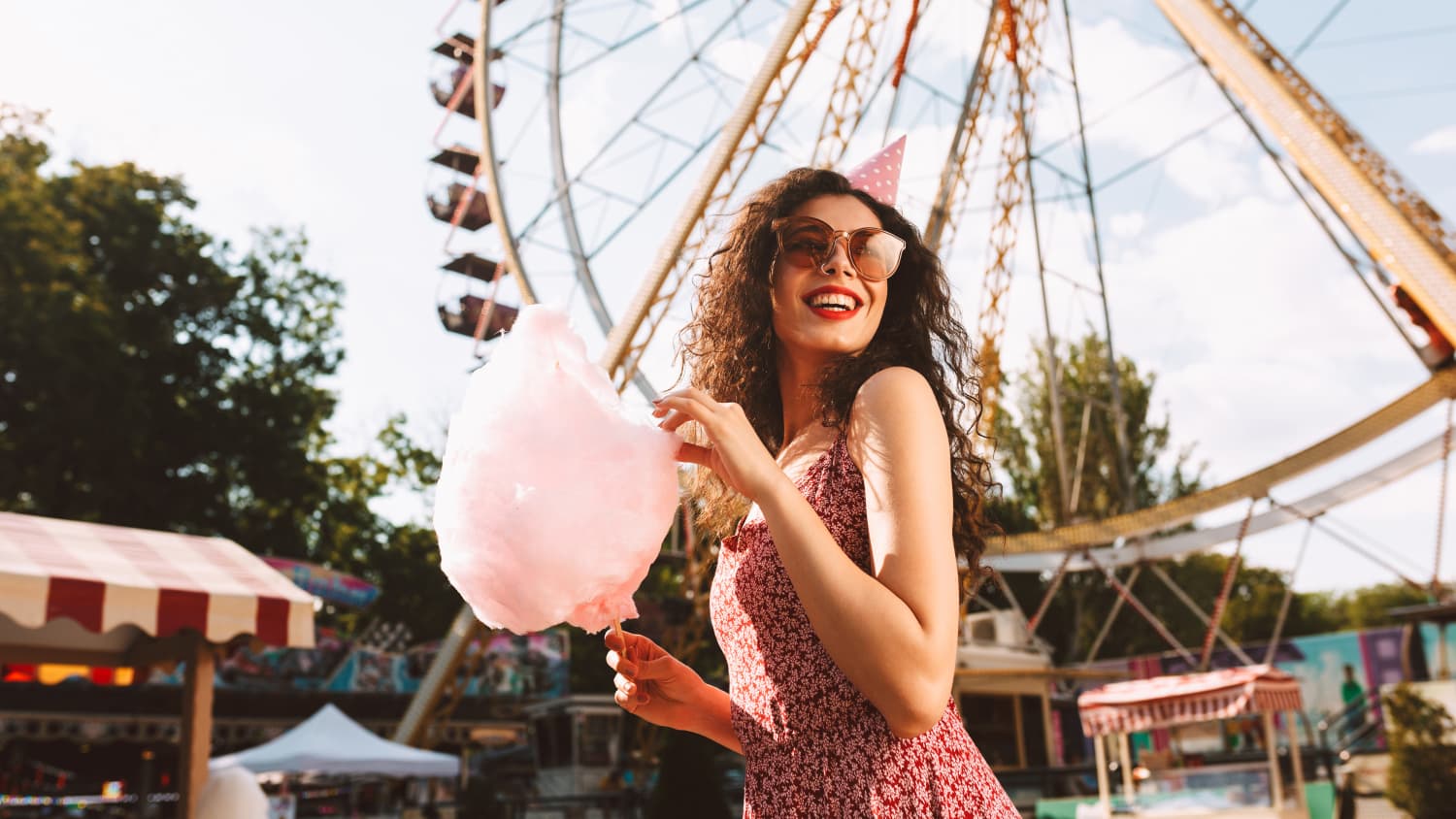 Junge Frau isst Zuckerwatte vor einem Riesenrad