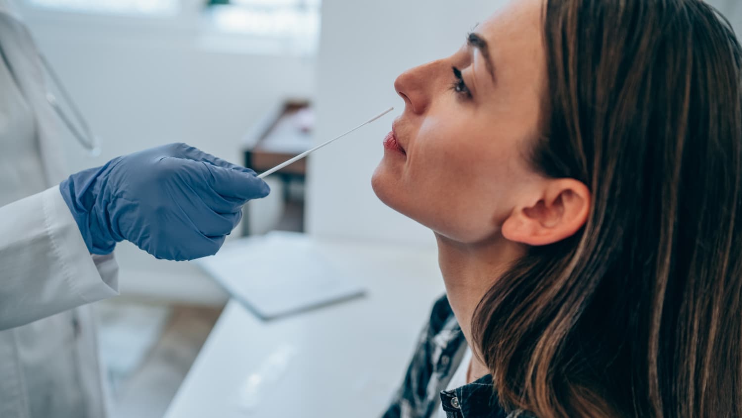 Ein Arzt führt einen PCR Test an einer Patientin durch