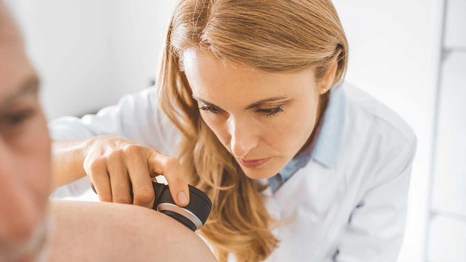 Eine Ärztin untersucht die Haut eines Patienten nach auffälligen Muttermalen