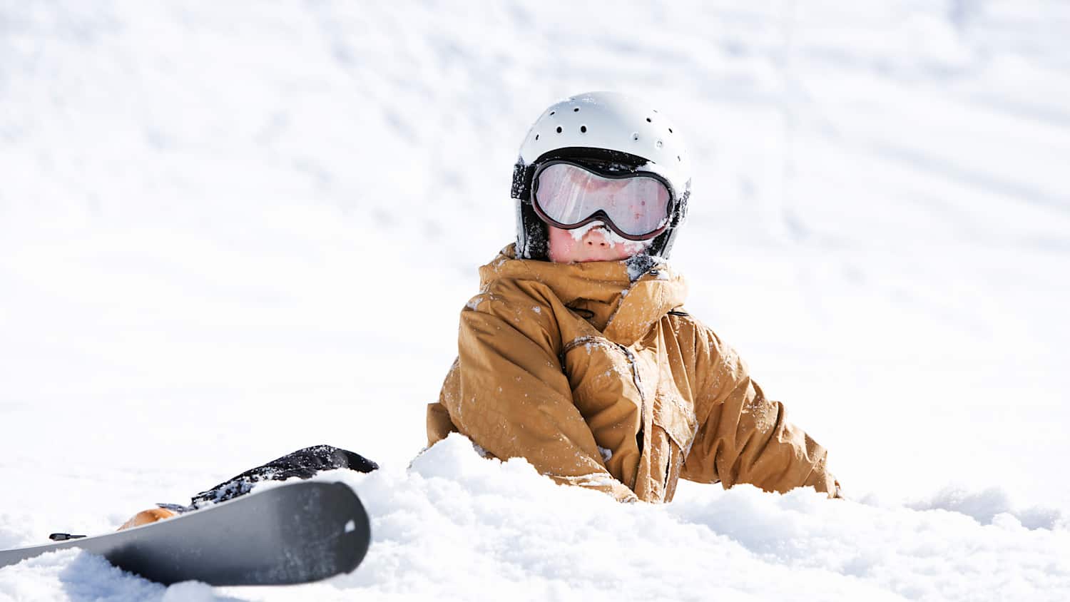 Ein Junge liegt nach einem Sturz mit Ski im Schnee