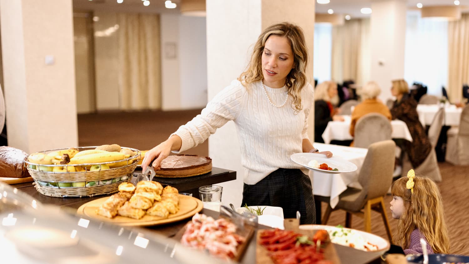 Eine Frau nimmt sich mit ihrer Tochter Essen vom Hotelbuffet