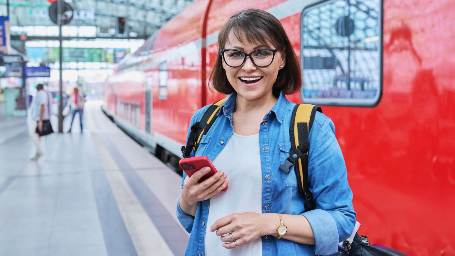 Eine Frau steht lachend am Bahnsteig