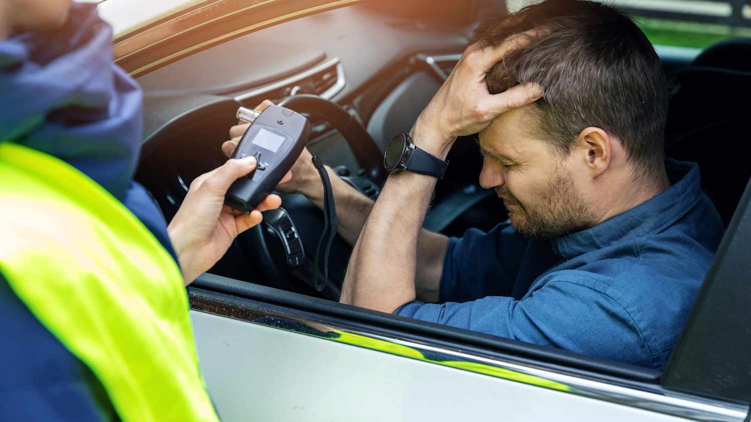 Ein Mann sitz verzweifelt bei einer Alkohol Kontrolle in seinem Auto
