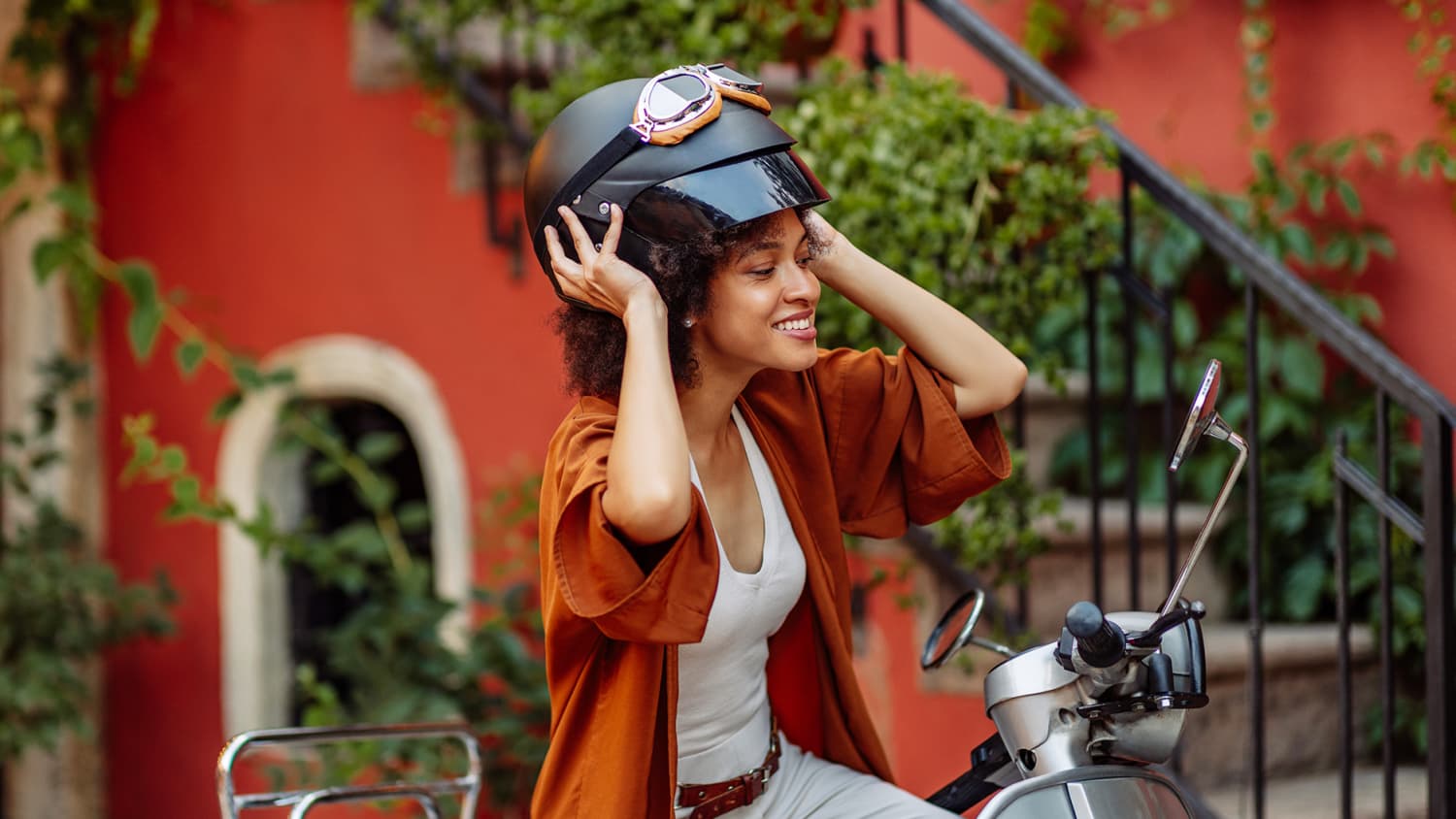 Eine attraktive junge Frau, die sich darauf vorbereitet, mit ihrer Vespa durch die Stadt zu fahren