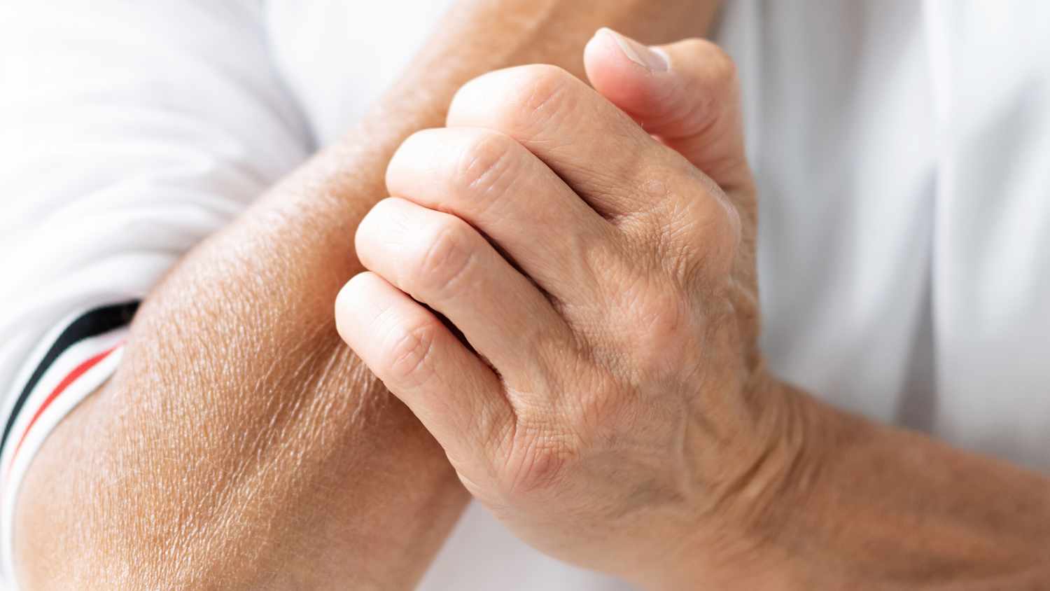 Ein Mann der sich am Handgelenk kratzt